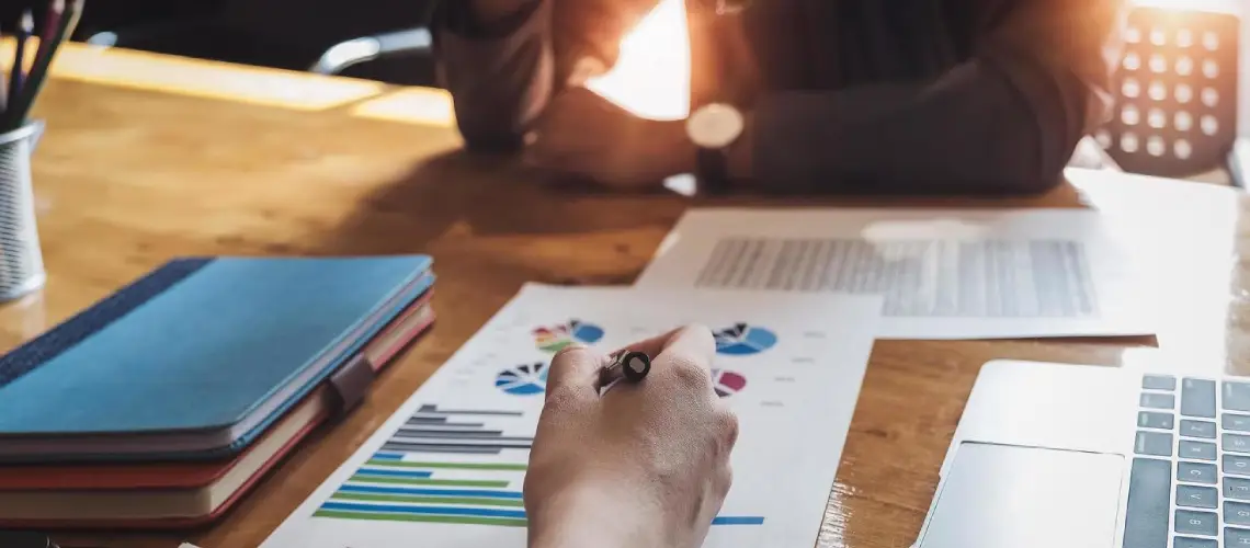 A Canberra-based business professional reviewing valuation reports on a laptop with charts and financial documents